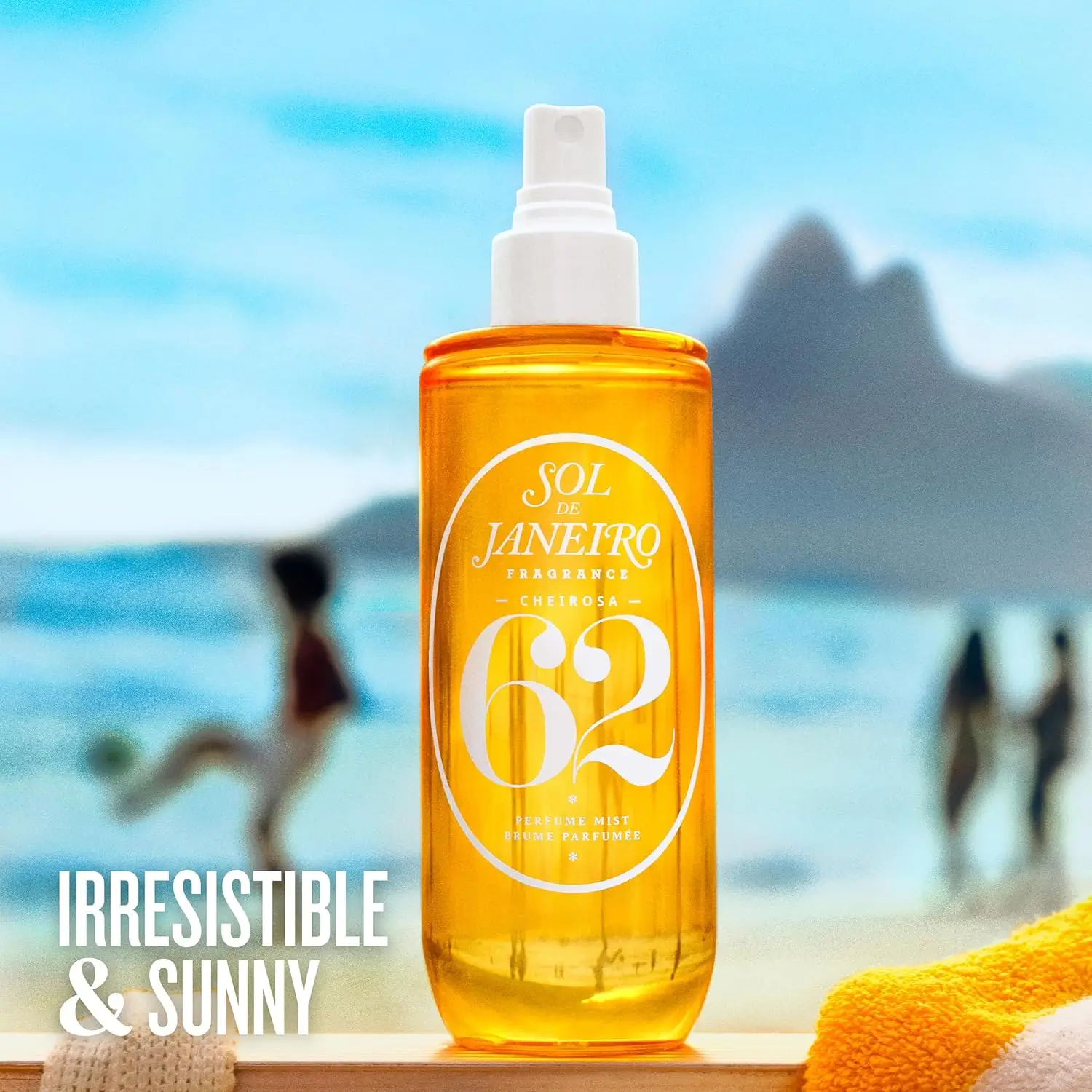 frasco do Sol de Janeiro Cheirosa 62 Perfume Mist em foco na praia, com mar azul e Morro Dois Irmãos ao fundo; texto “Irresistible & Sunny” no canto