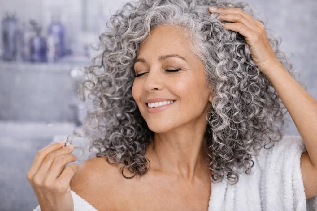 Mulher com cabelo cacheado grisalho brilhante e definido após matização
